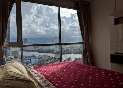 Bedroom with a large window overlooking the city skyline and river