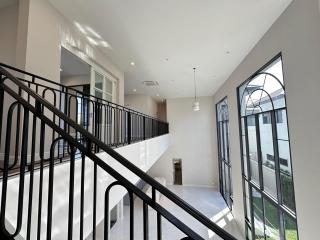 Spacious and bright upper-level living space with stair railing and large windows