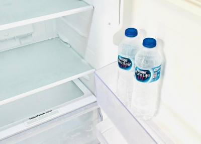 Two water bottles inside an open refrigerator in the kitchen