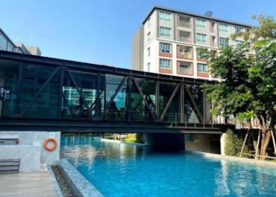 Modern pool area with a bridge and residential building in the background