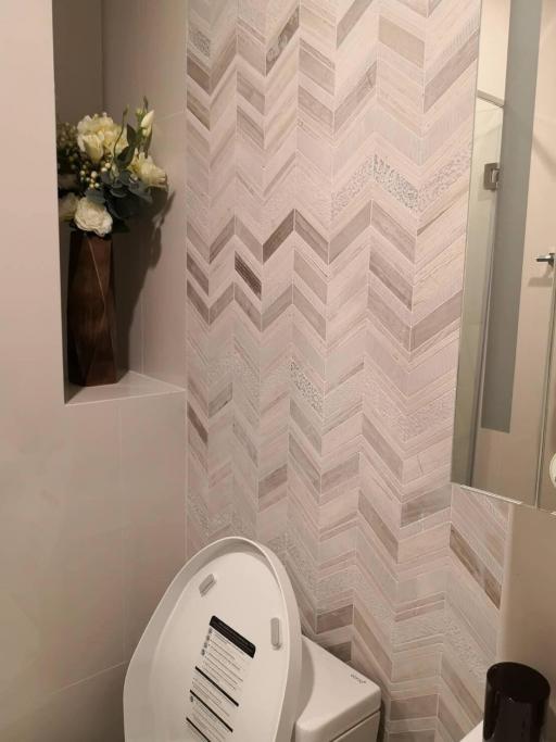 Modern bathroom with herringbone pattern tiled wall and white toilet