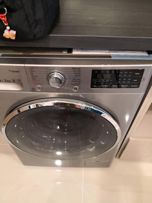 Front-loading silver washing machine in a modern laundry room