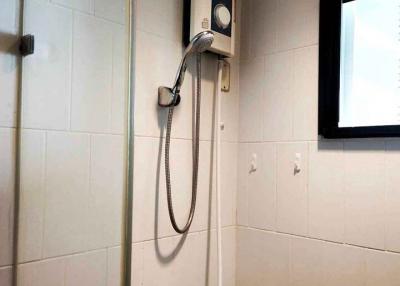 Wall-mounted water heater with shower in a tiled bathroom