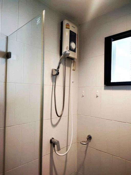 Wall-mounted water heater with shower in a tiled bathroom