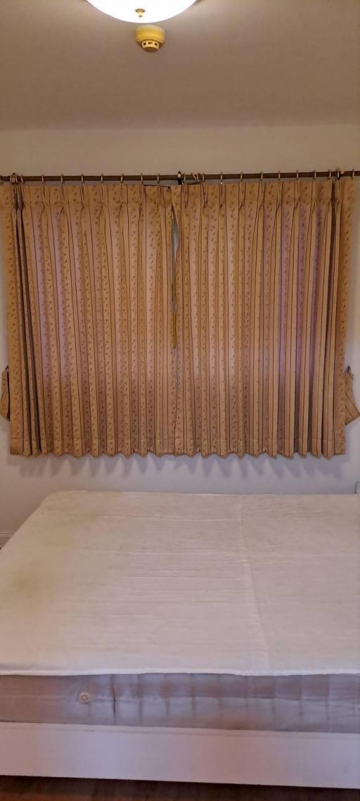 Neatly presented bedroom with large window dressed with patterned curtains