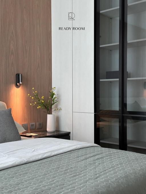 Modern bedroom with a comfortable bed, wooden wall panels, and sleek shelving unit