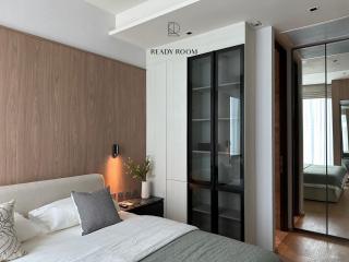 Contemporary bedroom with wooden accent wall and floor-to-ceiling glass wardrobe