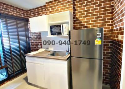 Compact modern kitchen with stainless steel appliances and brick wall