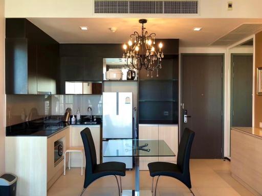 Modern kitchen with dining area, featuring black cabinetry and natural light