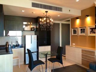 Modern kitchen with adjacent dining area featuring a chandelier, stainless steel appliances, and wooden cabinets