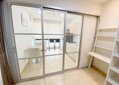 Modern kitchen viewed through glass door with glossy tiled floor and white shelving unit
