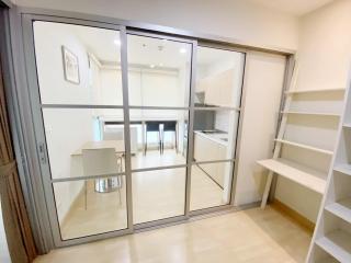 Modern kitchen viewed through glass door with glossy tiled floor and white shelving unit