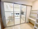 Modern kitchen viewed through glass door with glossy tiled floor and white shelving unit