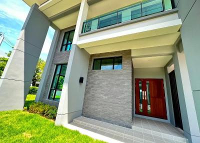 Modern two-story house with a red front door and a landscaped yard