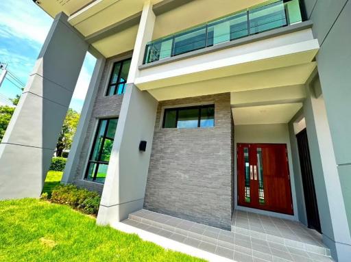 Modern two-story house with a red front door and a landscaped yard