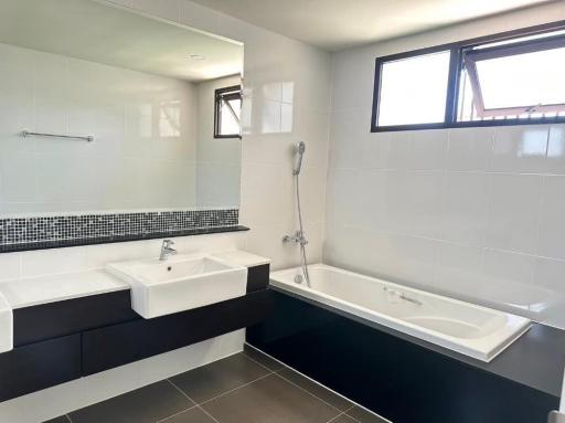 Modern bathroom with dual sinks, bathtub, and separate shower area