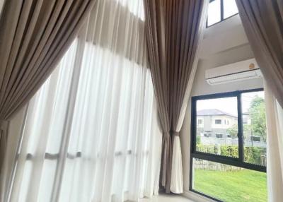 Bright and airy living room with tall curtains and a view of the garden