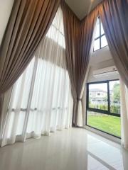 Bright and airy living room with tall curtains and a view of the garden