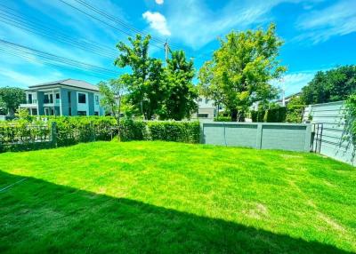 Spacious backyard with green lawn and clear blue sky