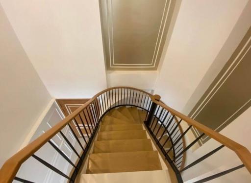 Upward view of a modern staircase with wooden handrails and clean lines