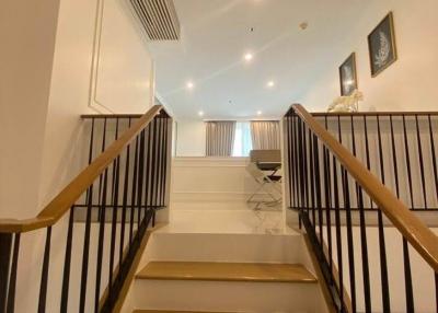 Modern staircase with elegant finishes leading to an upper-level living space with ample lighting