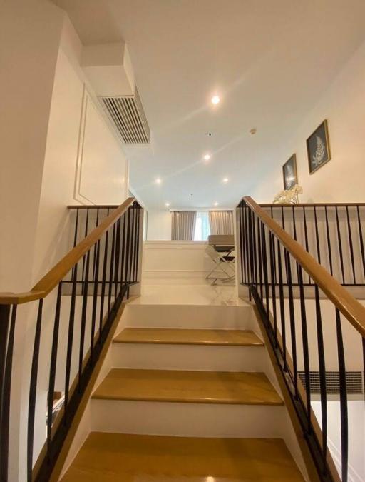 Modern staircase with elegant finishes leading to an upper-level living space with ample lighting