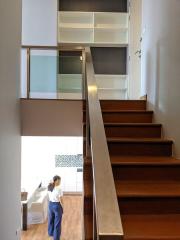 Interior view of a modern home staircase with metallic handrail leading to an upper-level living area