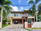 Modern two-story house with a gated entrance and palm trees