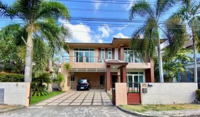 Modern two-story house with a gated entrance and palm trees