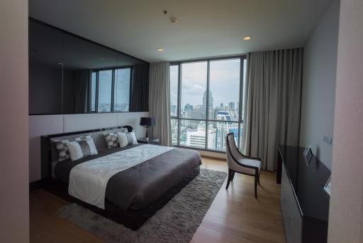 Modern bedroom with a panoramic city view through floor-to-ceiling windows