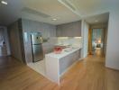 Modern kitchen with wooden flooring and an open layout leading to a well-lit living area