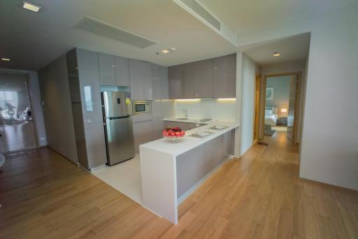 Modern kitchen with wooden flooring and an open layout leading to a well-lit living area