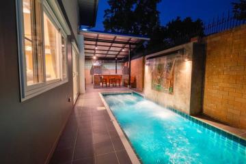 Cozy outdoor patio with illuminated swimming pool and dining area at dusk