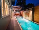 Cozy outdoor patio with illuminated swimming pool and dining area at dusk