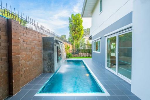 Cozy backyard with a private pool and modern waterfall feature