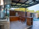 Spacious outdoor kitchen with modern appliances and adjacent dining area overlooking a pool and waterfall