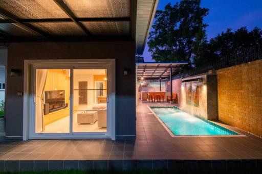 Modern home exterior with swimming pool and patio area during evening
