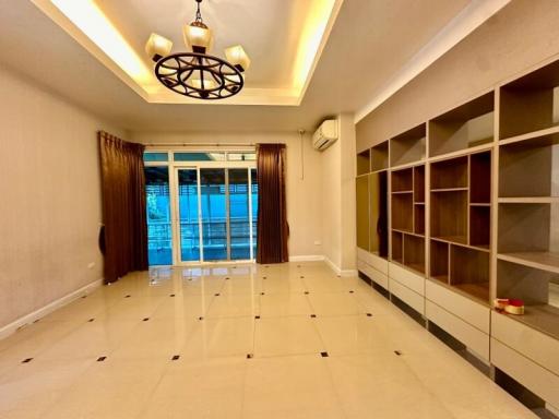 Spacious living room with modern chandelier, built-in shelves and large windows