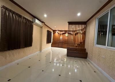 Spacious living room with glossy tiled flooring and wooden staircase