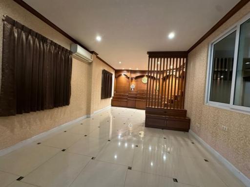 Spacious living room with glossy tiled flooring and wooden staircase