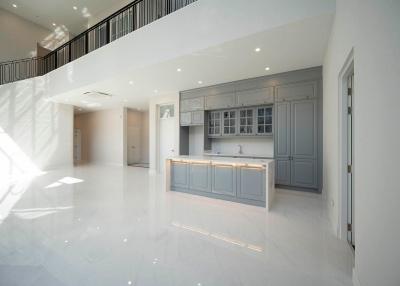 Spacious modern kitchen with bright natural light, featuring a large island and glossy floor tiles