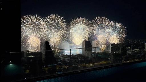 Spectacular nighttime view from a high-rise balcony overlooking a city with fireworks