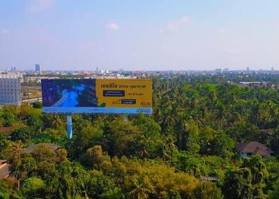 Expansive view of a tropical outdoor area with lush greenery and a billboard