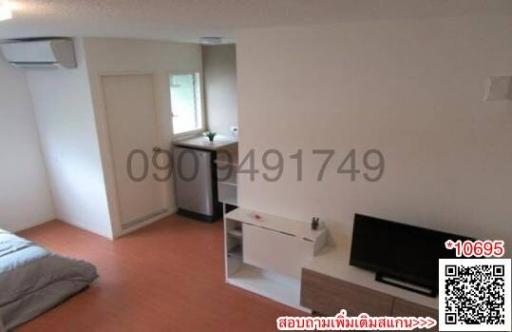 Compact bedroom with bed, TV stand, and kitchenette
