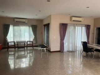 Spacious and well-lit living room with glossy tiled flooring and multiple seating options