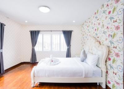 Bright bedroom interior with floral wallpaper and hardwood floors