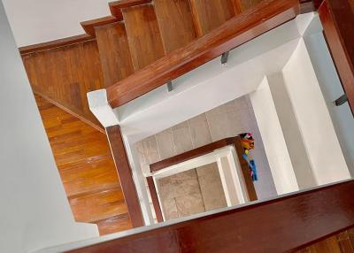 View from the top of a wooden staircase with polished handrails leading down to a tiled foyer