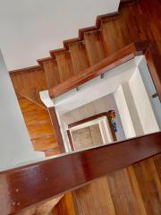 View from the top of a wooden staircase with polished handrails leading down to a tiled foyer