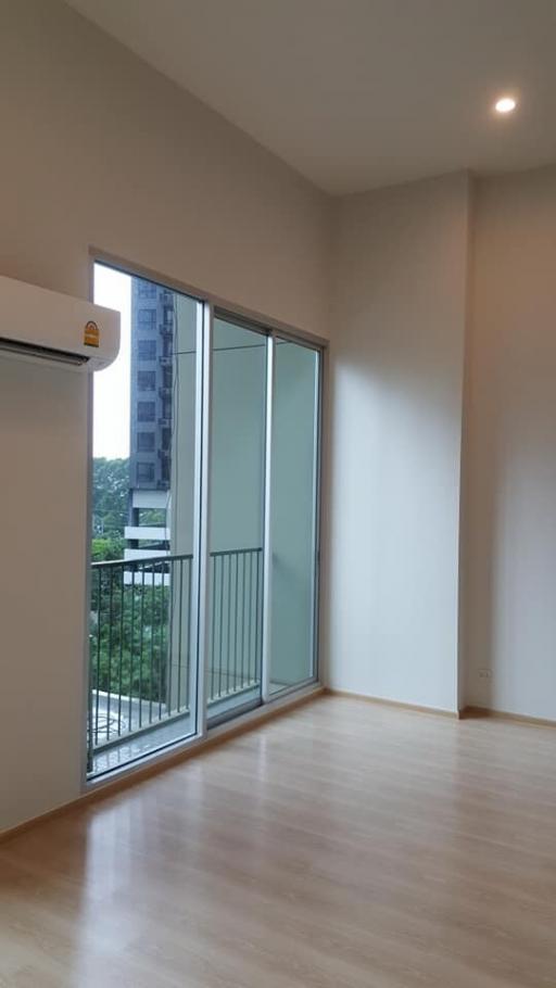 Empty bedroom with large window and hardwood flooring