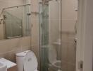 Modern bathroom with glass shower enclosure and beige tiles